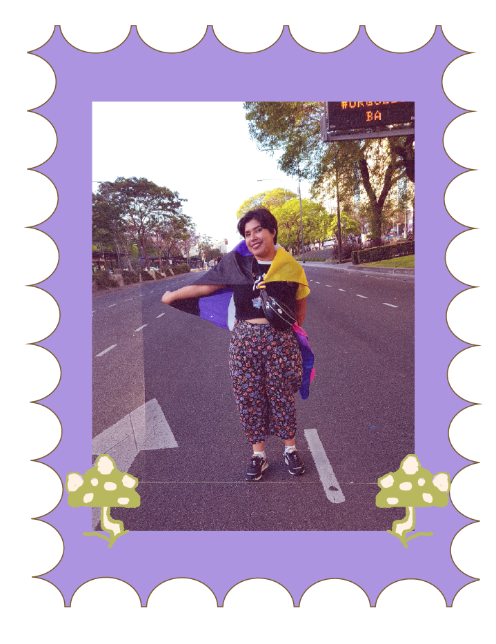 persona parada en la calle sonrriendo mientras muestra su bandera no binaria